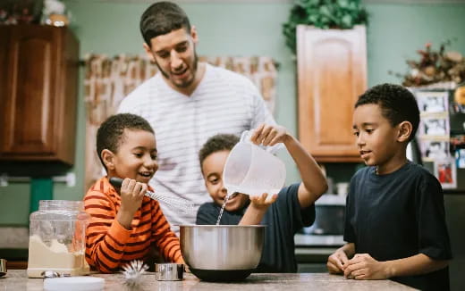 a person pouring a liquid into a bowl with a group of boys