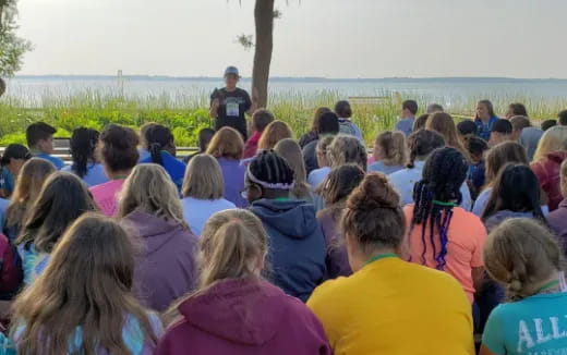 a group of people sitting on the ground looking at a person standing