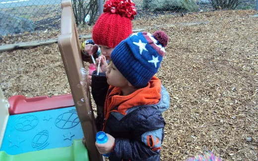 a child in a hat and coat sitting on a bench
