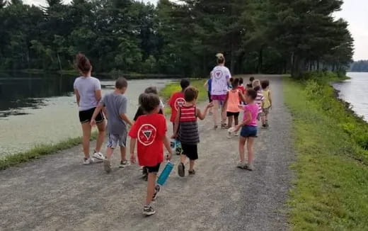 a group of people walking on a path by water