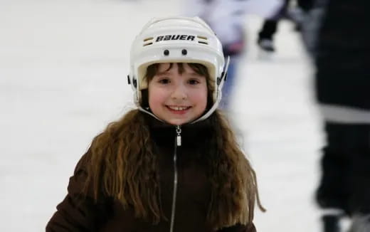 a young girl wearing a helmet and smiling at the camera