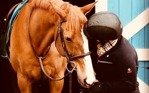 a person in a helmet next to a horse