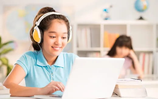 a young girl wearing headphones and using a laptop