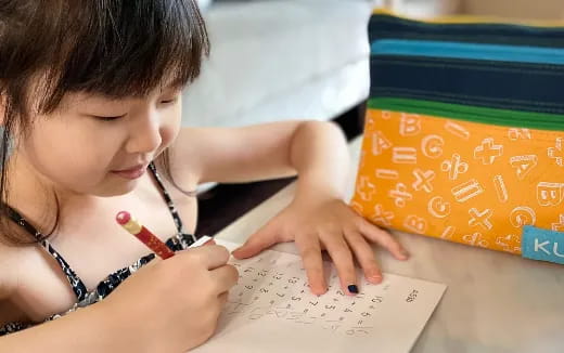 a young girl writing on a piece of paper
