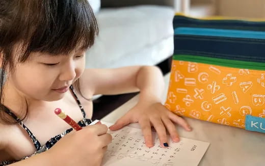 a young girl writing on a piece of paper