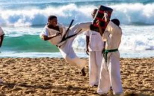 a group of men in white karate uniforms on a beach