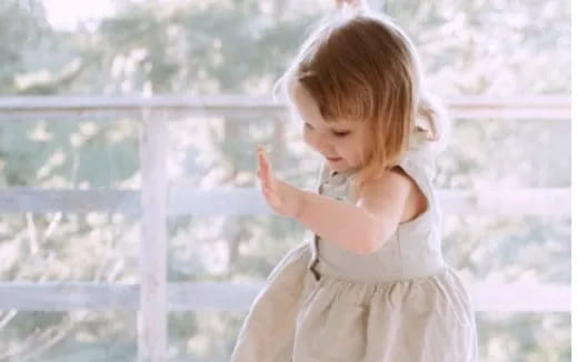 a little girl standing in front of a window