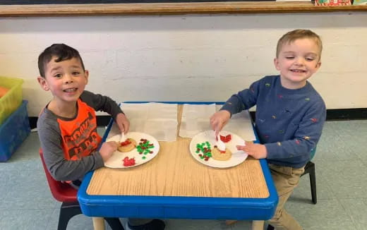 two boys sitting at a table with food on it