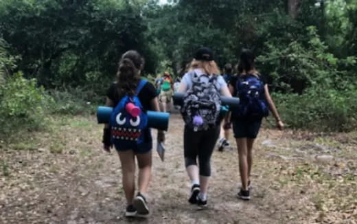 a group of people walking on a dirt path in the woods
