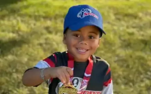 a boy smiling and holding a trophy