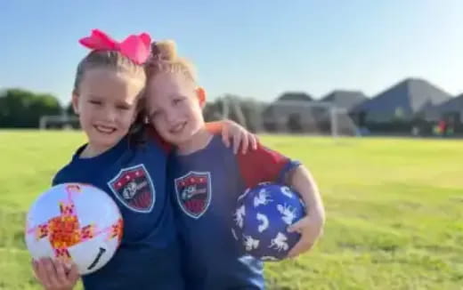 a couple of girls holding a football ball