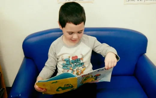 a child sitting on a blue couch reading a book