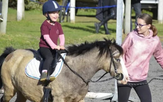 a person leading a girl on a horse