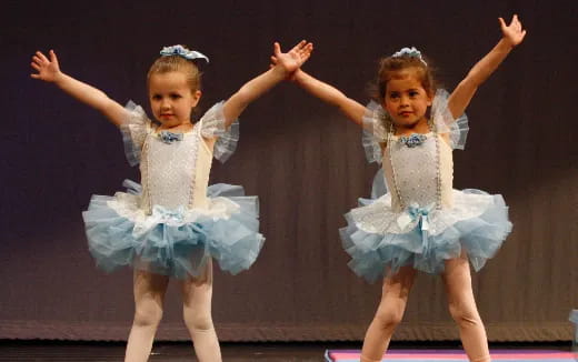 two girls wearing blue dresses and dancing