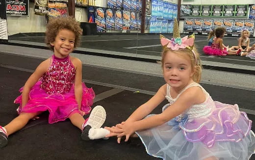 a couple of girls in dresses sitting on the floor in a store