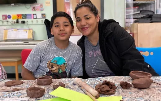 a woman and a boy sitting at a table with a sculpture