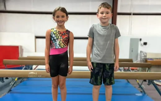 a boy and girl standing next to a pool