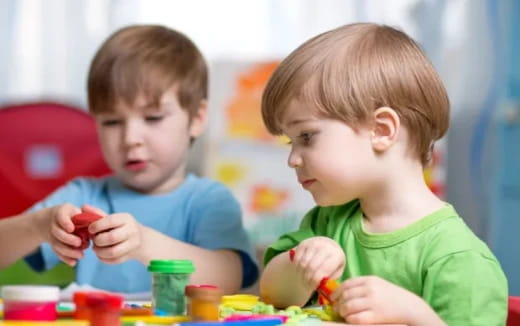a couple of boys sitting at a table with toys