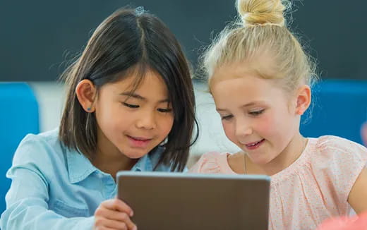 a couple of children looking at a laptop