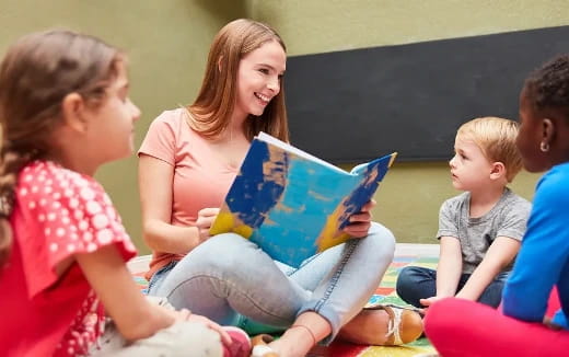 a person reading a book to a group of children