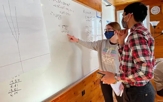 a few people writing on a whiteboard
