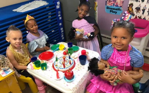 a group of children sitting at a table with a cake