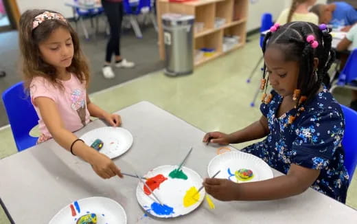 a couple of girls sitting at a table with a cake