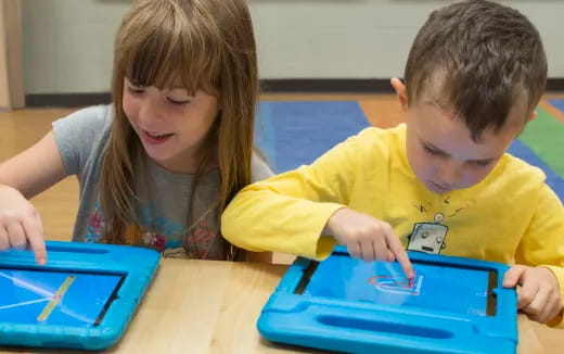 a boy and girl looking at a tablet