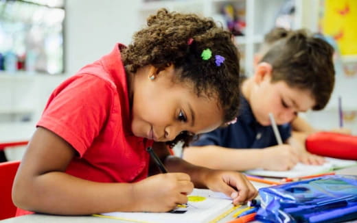 a young girl and a young boy coloring on a paper