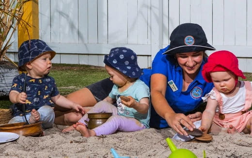 a person and several children playing in the sand