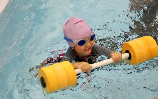a baby in a pool with a toy shovel and a bucket