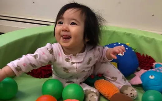a baby lying on a bed with balls