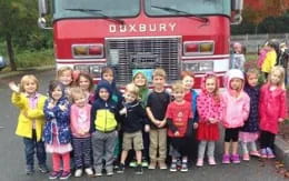 a group of children posing for a photo in front of a firetruck