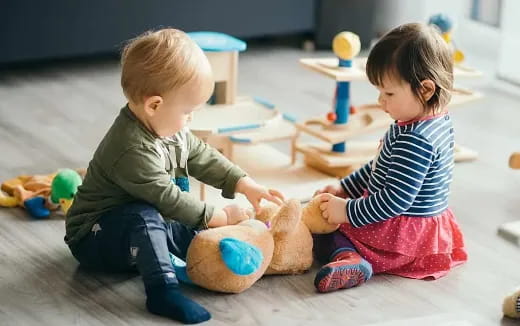 a couple of children playing with a stuffed animal
