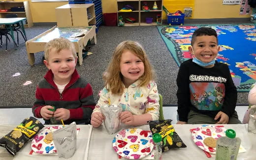 a group of children sitting at a table with toys