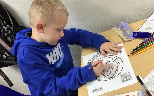 a child sitting at a desk writing on a book
