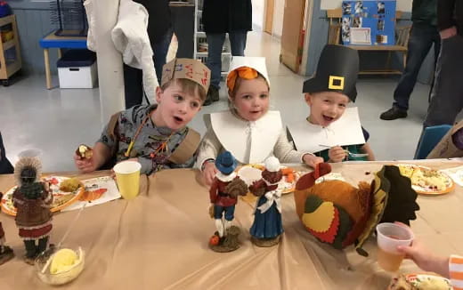 a group of kids sitting at a table with food
