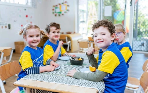 a group of kids sitting at a table eating
