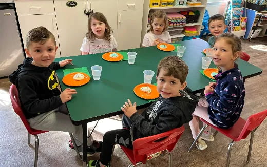 a group of children sitting around a table eating food