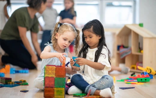 a couple of young girls playing with toys on the floor