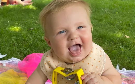 a baby with a yellow toy in its mouth