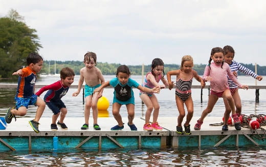 a group of children jumping into a pool