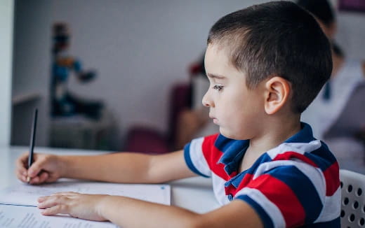 a young boy writing on a paper