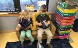 a boy and girl sitting on a couch with a game console