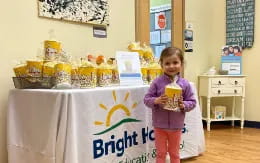 a girl standing next to a table with a sign