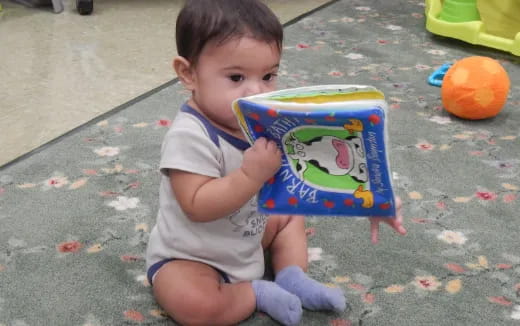 a baby sitting on the sidewalk reading a book