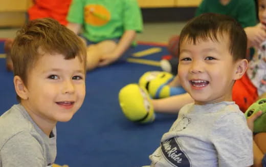 a couple of young boys playing with tennis balls