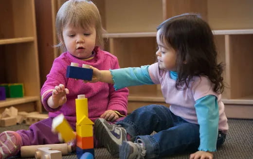 a couple of young girls playing with a cell phone