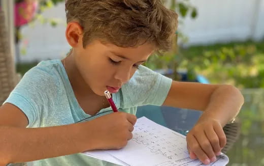 a young boy writing on a piece of paper