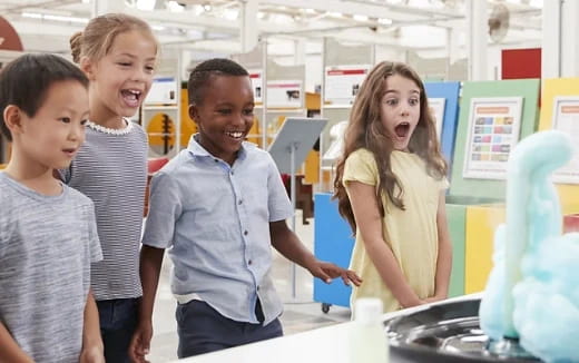 a group of kids standing in front of a computer
